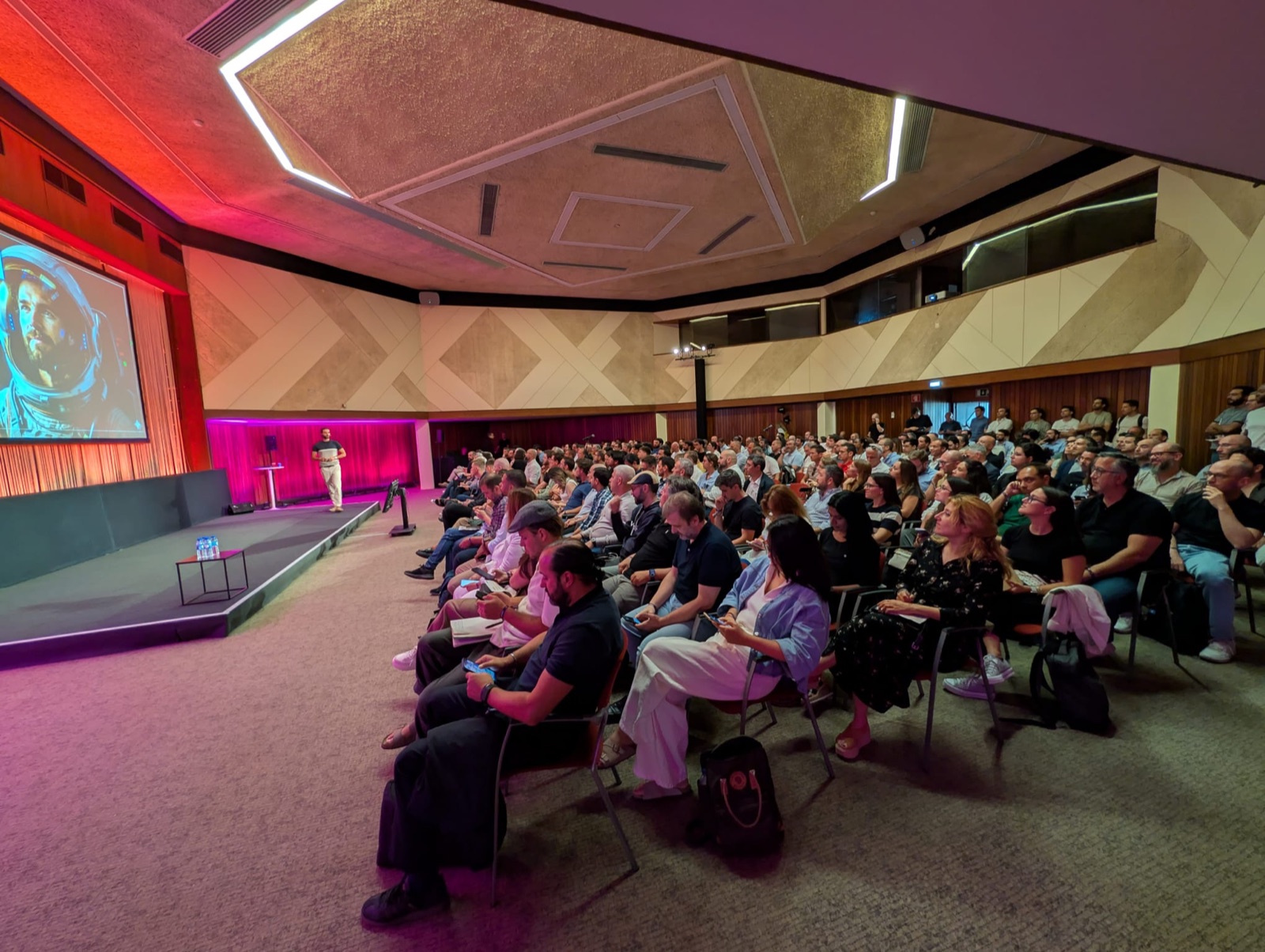 Rui Vas on a pink-lit stage at the Lisbon AI Summit, seen with the seated audience