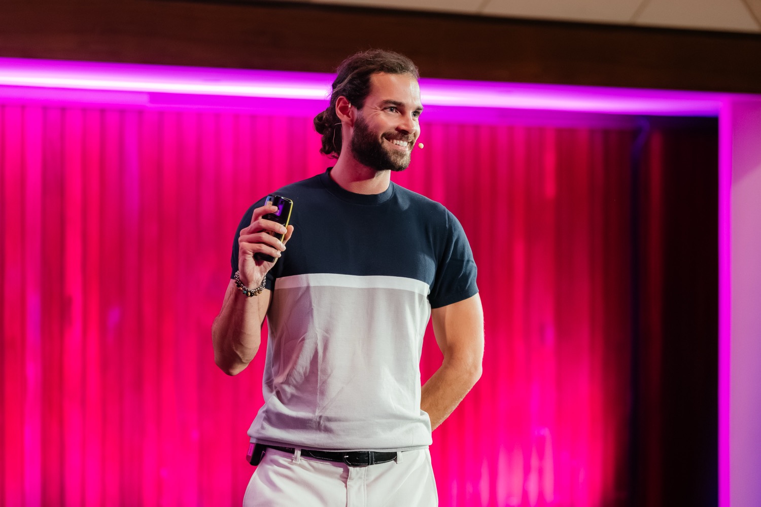 Rui Vasconcelos speaking on stage, lit by magenta neon light